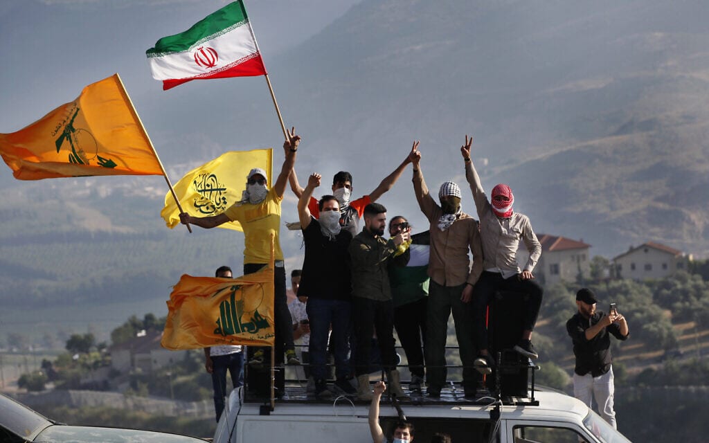 תומכי חזבאללה מניפים את דגלי הארגון ואיראן במהלך הפגנה בגבול לבנון–ישראל ליד כפר כילא, לבנון, 14 במאי 2021 (צילום: AP Photo/ Mohammed Zaatari)