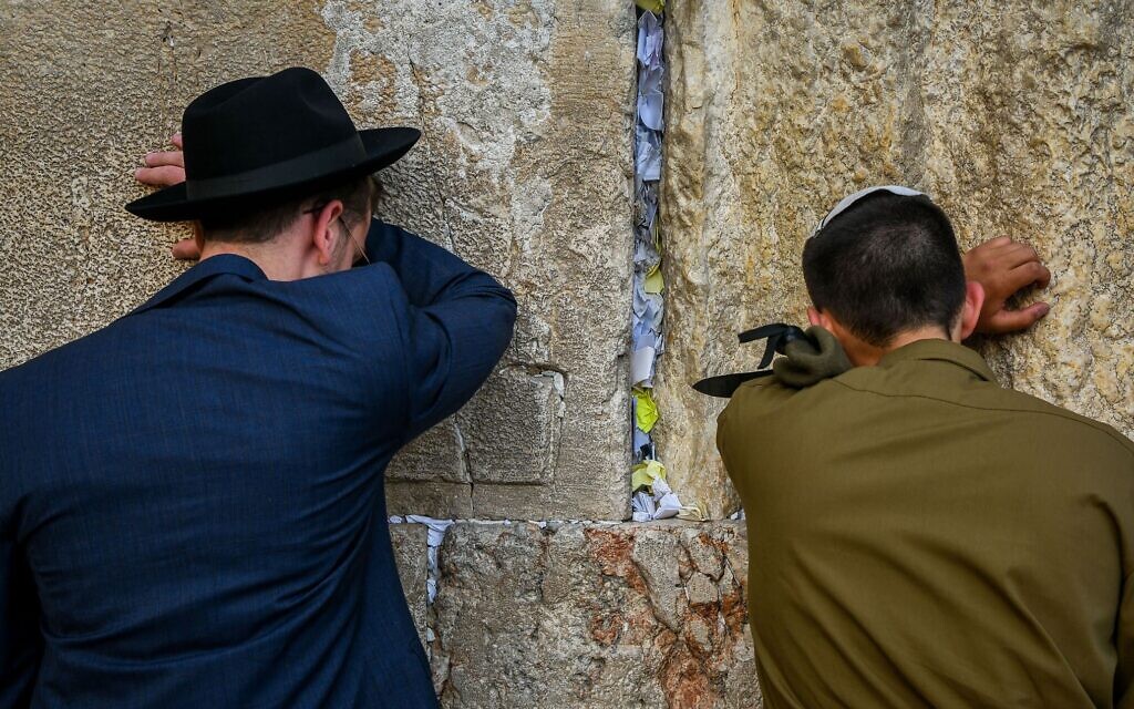 חייל מתפלל לצד בחור חרדי בכותל המערבי בירושלים, 17 במאי 2023 (צילום: אריה לייב אברמס/פלאש90)