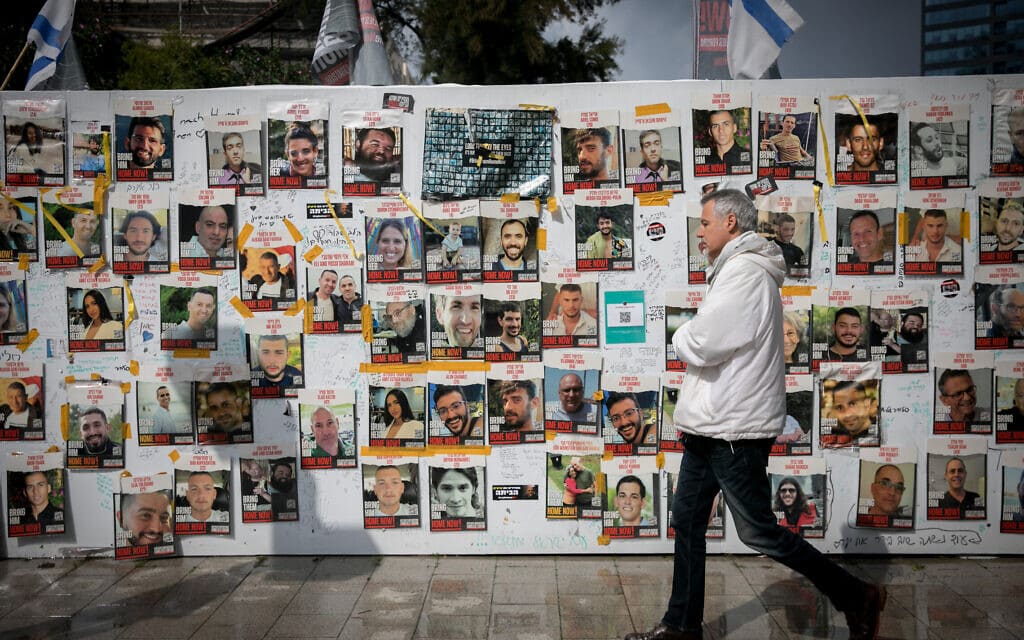 עובר אורח חולף בתל אביב על פני תמונותיהם של החטופים המוחזקים ברצועת עזה, 14 בפברואר 2024 (צילום: מרים אלסטר/פלאש90)