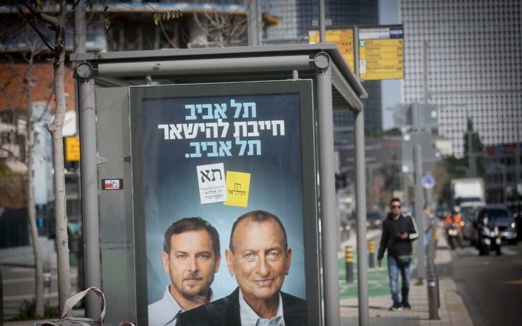 שלט בחירות של רון חולדאי ושל רשימת תל אביב אחת על תחנת אוטובוס בעיר, 15 בינואר 2024 (צילום: מרים אלסטר/פלאש90)