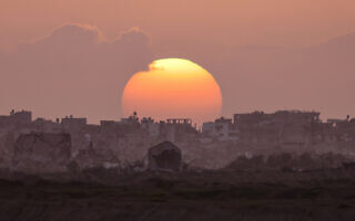 השמש שוקעת מאחורי ההריסות בעזה, 3 במרץ 2024 (צילום: Menahem KAHANA / AFP)