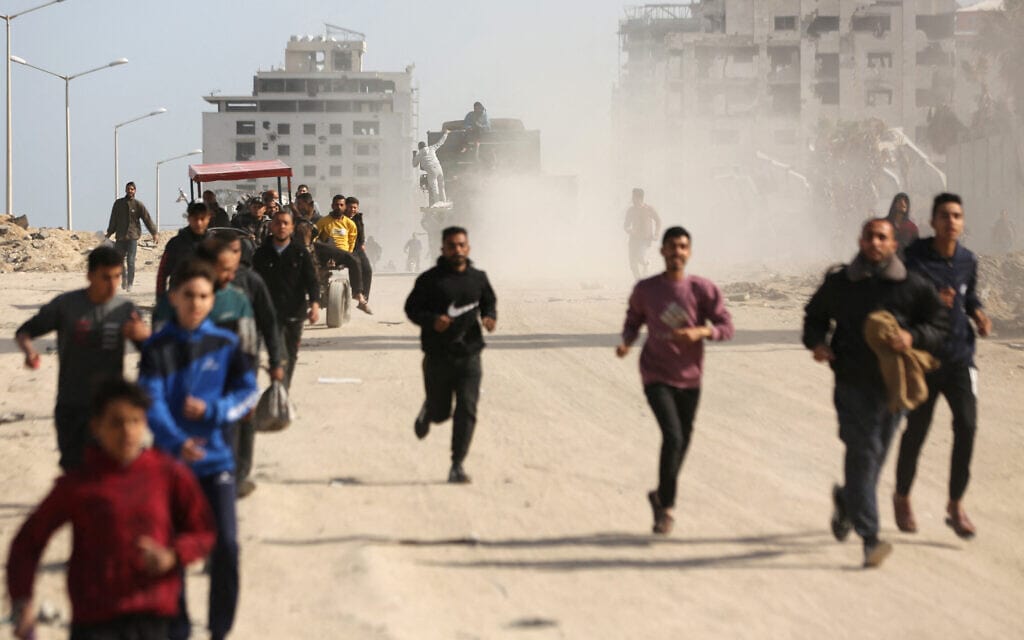 פלסטינים רצים בעיר עזה בשעה שסיוע הומניטרי מוכנס ליישוב, 6 במרץ 2024 (צילום: AFP)