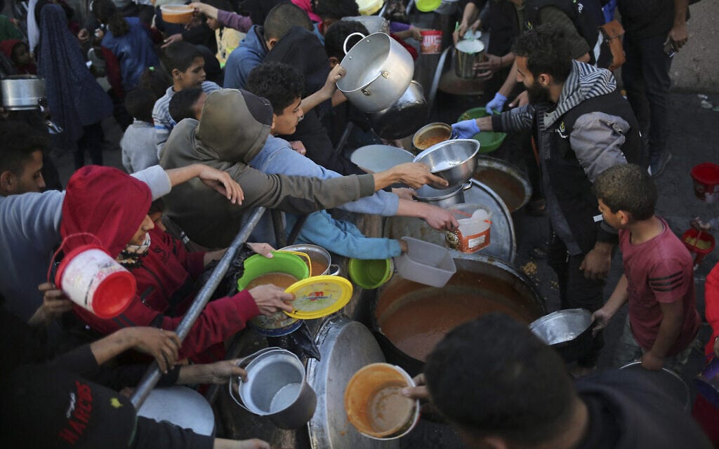 עקורים פלסטינים אוספים מזון שנתרם על ידי ארגון צדקה לפני ארוחת אפטאר ביום הראשון של חודש רמדאן, בעיר רפיח שבדרום עזה, 11 במרץ 2024 (צילום: AFP)