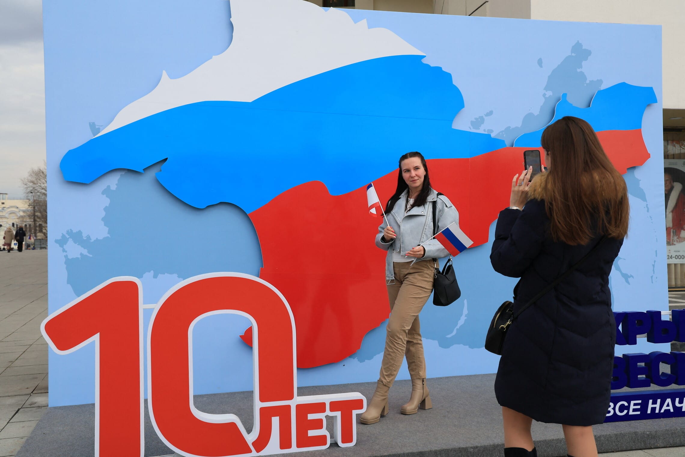 אישה מצטלמת עם מיצג לציון 10 שנים לכיבוש הרוסי של חצי האי קרים, סימפרופול, 13 במרץ 2024. (צילום: STRINGER / AFP)