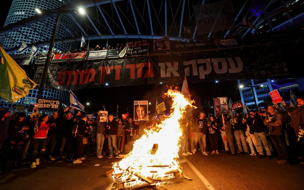 מפגינים למען שחרור חטופים הדליקו מדורה מחוץ לבסיס הקריה בדרך בגין בתל אביב, 16 במרץ 2024 (צילום: JACK GUEZ / AFP)