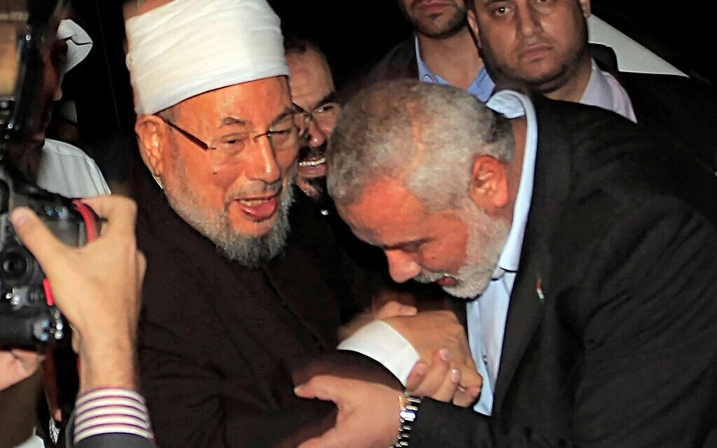 מנהיג חמאס אסמאעיל הנייה מנשק את ידו של איש הדת המצרי ויו&quot;ר האיחוד העולמי של חכמי הדת המוסלמים השייח&#039; יוסף אל־קרדאווי במעבר רפיח, 8 במאי 2013 (צילום: Said Khatib/AFP)