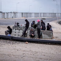 פועלים פלסטינים מהגדה המערבית ממתינים למעסיקים במעבר אייל ליד קלקיליה, 20 בפברואר 2022 (צילום: AP Photo/Oded Balilty)