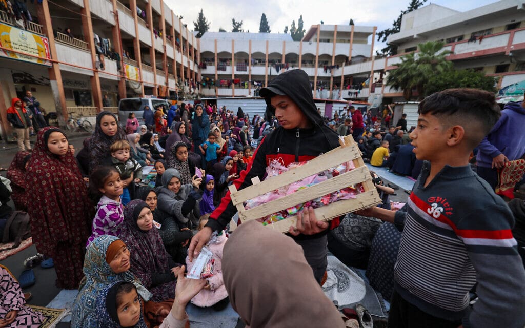 חלוקת ממתקים לכבוד עיד אל-פיטר לילדים במבנה בית ספר שהפך למקלט עבור העקורים העזתים ברפיח, 10 באפריל 2024 (צילום: MOHAMMED ABED / AFP)