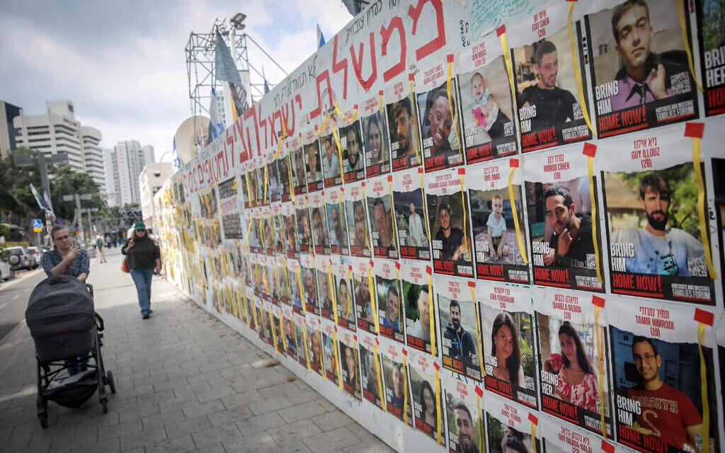 אנשים חולפים על פני תמונות של ישראלים שעדיין מוחזקים בידי מחבלי חמאס בעזה, כיכר החטופים בתל אביב, 14 במרץ 2024 (צילום: מרים אלסטר/פלאש90)