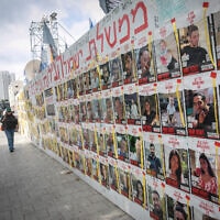 אנשים חולפים על פני תמונות הישראלים המוחזקים בידי מחבלי חמאס בעזה, כיכר החטופים בתל אביב, 14 במרץ 2024 (צילום: מרים אלסטר/פלאש90)