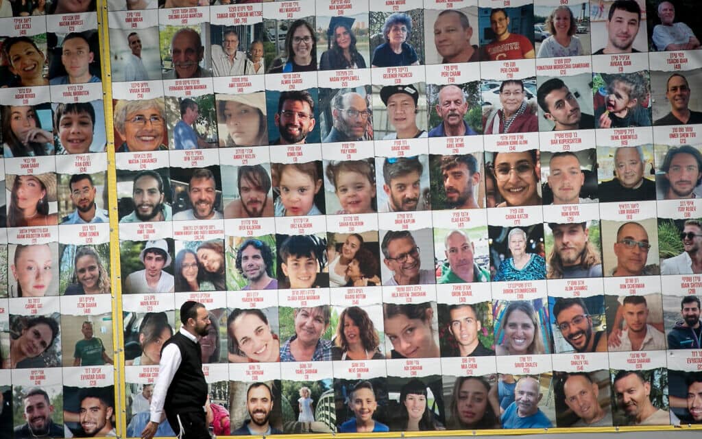 עובר אורח חולף בתל אביב על פני תמונותיהם של חטופים וחטופים ששוחררו מהשבי ברצועת עזה, 9 באפריל 2024 (צילום: מרים אלסטר/פלאש90)