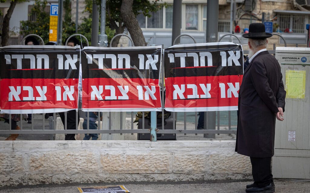 גבר חרדי עובר ליד שלט נגד הגיוס לצה"ל, ירושלים, 11 באפריל 2024 (צילום: חיים גולדברג/פלאש90)