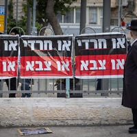 גבר חרדי עובר ליד שלט נגד הגיוס לצה"ל, ירושלים, 11 באפריל 2024 (צילום: חיים גולדברג/פלאש90)