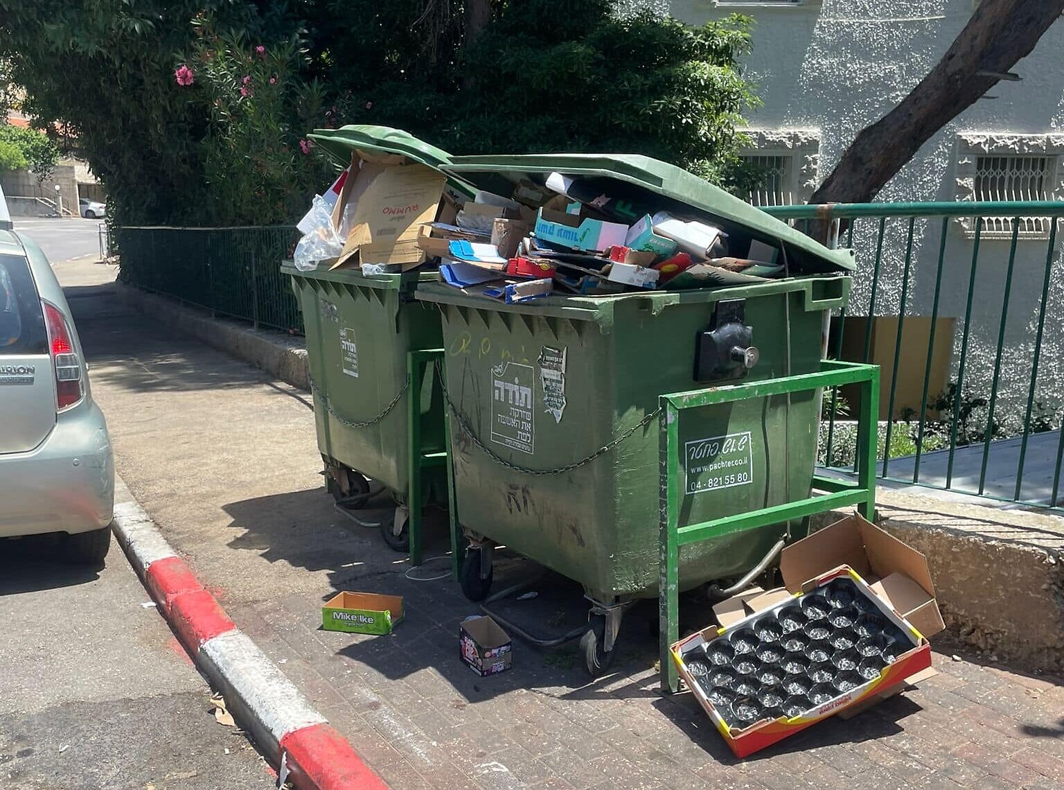 פחי זבל מלאים באשפה ופתוחים באחוזה בחיפה. מאי 2024 (צילום: קארין ארד)