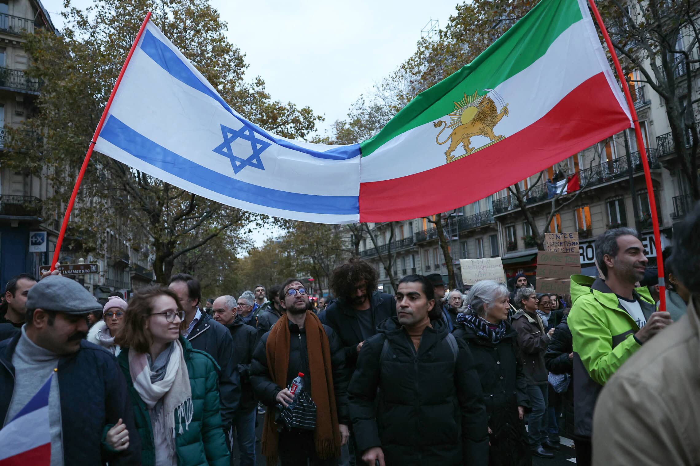 מפגינים מניפים את דגלי ישראל ואיראן בצעדה נגד אנטישמיות בפריז, 12 בנובמבר 2023 (צילום: Thomas SAMSON / AFP)