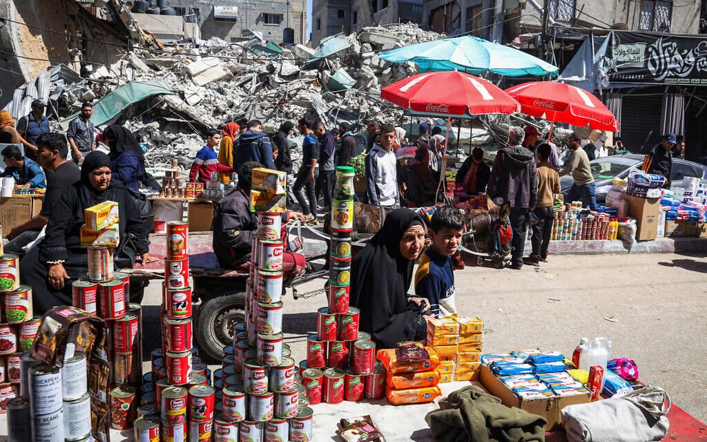 פלסטינים בשוק מאולתר ליד הריסות בניין במהלך חודש רמדאן ברפיח, דרום רצועת עזה, 12 במרץ 2024 (צילום: AFP)