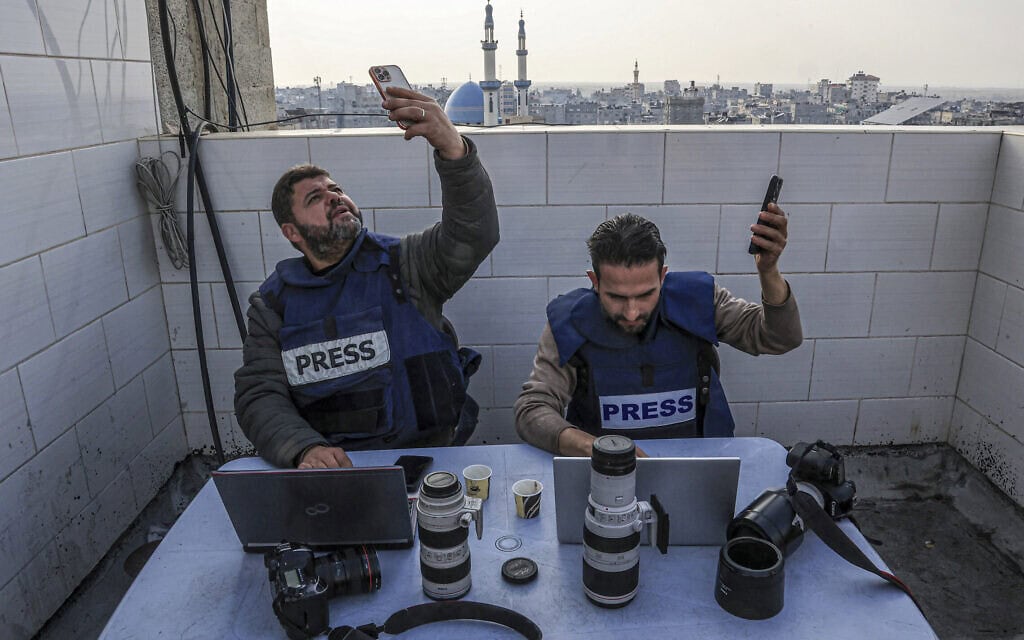 עיתונאים ברצועת עזה מנסים למצוא חיבור סלולרי באזור רפיח, 27 בדצמבר 2023 (צילום: SAID KHATIB / AFP)