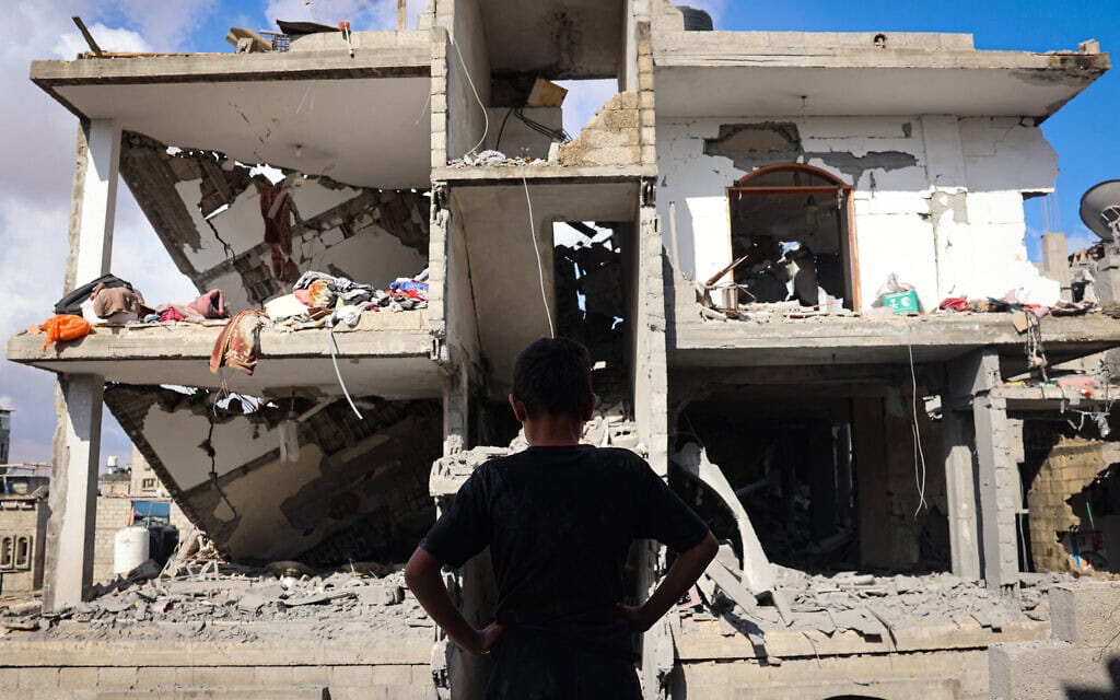 צעיר פלסטיני מול בניין שנהרס בפצצה ישראלית על מחוז טל א-סולטן ברפיח בדרום רצועת עזה ב-7 במאי 2024 (צילום: AFP)