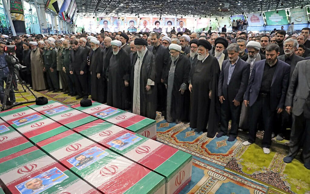 המנהיג העליון של איראן עלי חמינאי (במרכז) מוביל תפילה לצד ארונותיהם של ההרוגים בהתרסקות המסוק, ביניהם הנשיא אבראהים ראיסי. 22 במאי 2024 (צילום: IRANIAN SUPREME LEADER&#039;S WEBSITE / AFP)