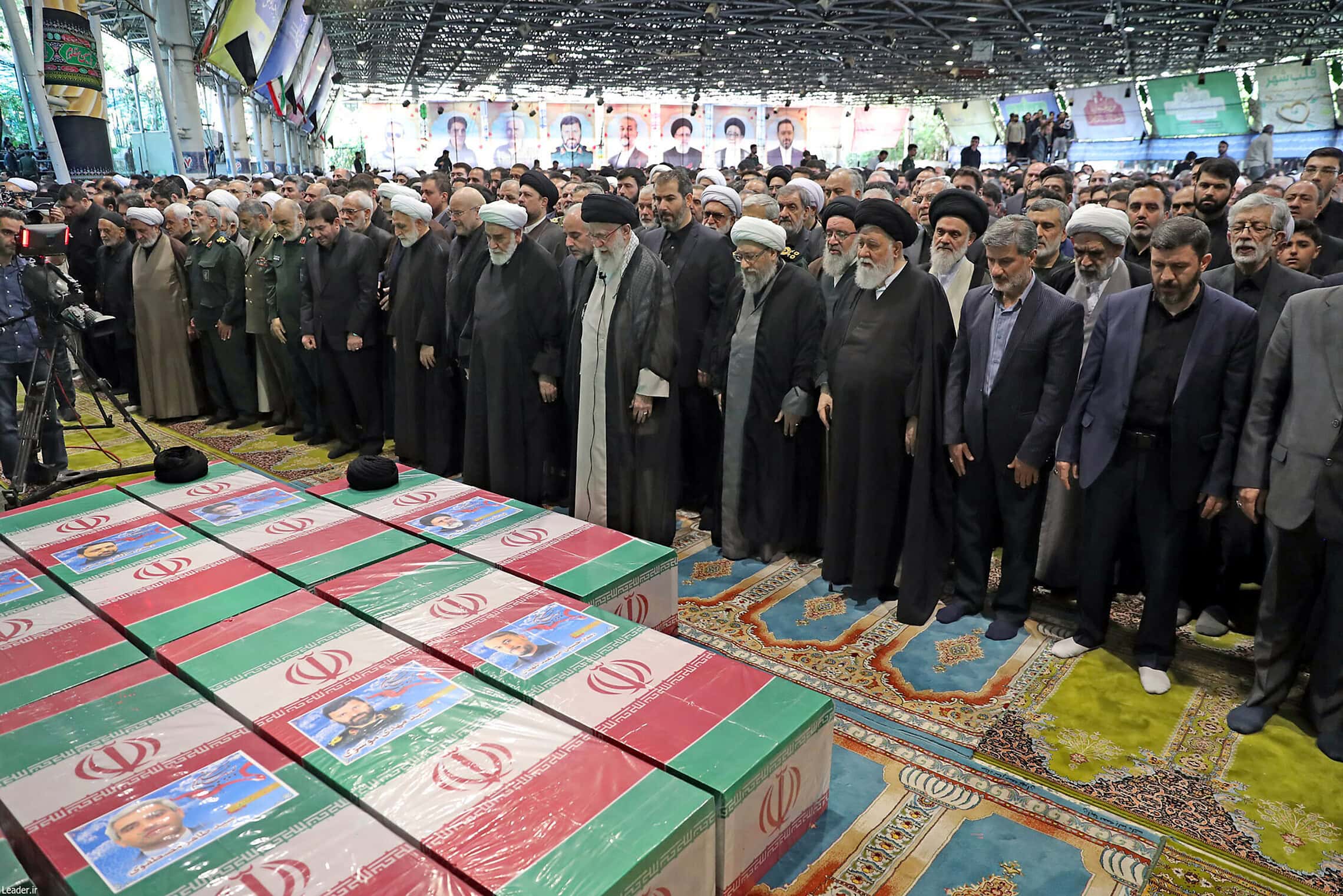 המנהיג העליון של איראן עלי חמינאי (במרכז) מוביל תפילה לצד ארונותיהם של ההרוגים בהתרסקות המסוק, ביניהם הנשיא אבראהים ראיסי. 22 במאי 2024