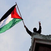 סטודנט מניף את דגל פלסטין על הגג של בניין המילטון בקמפוס של אוניברסיטת קולומביה בניו יורק, 30 באפריל 2024