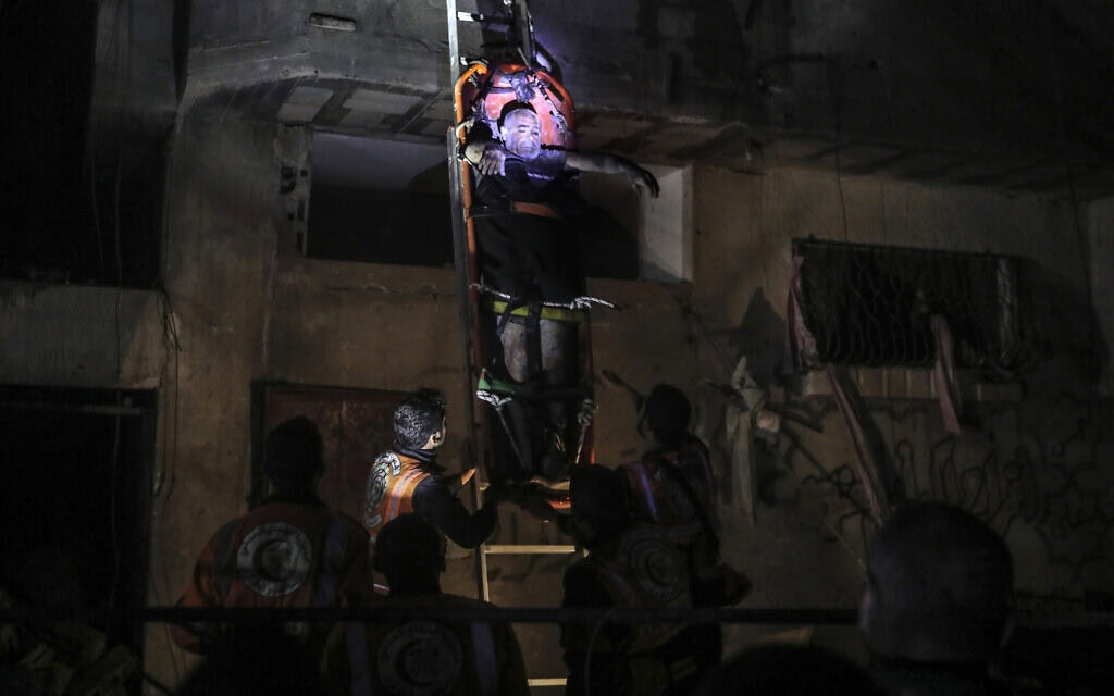 אנשי כוחות ההגנה האזרחית הפלסטינית מפנים תושבים במבנה ברפיח שנפגעו בתקיפה ישראלית, 4 במאי 2024 (צילום: AP Photo/Ismael Abu Dayyah)