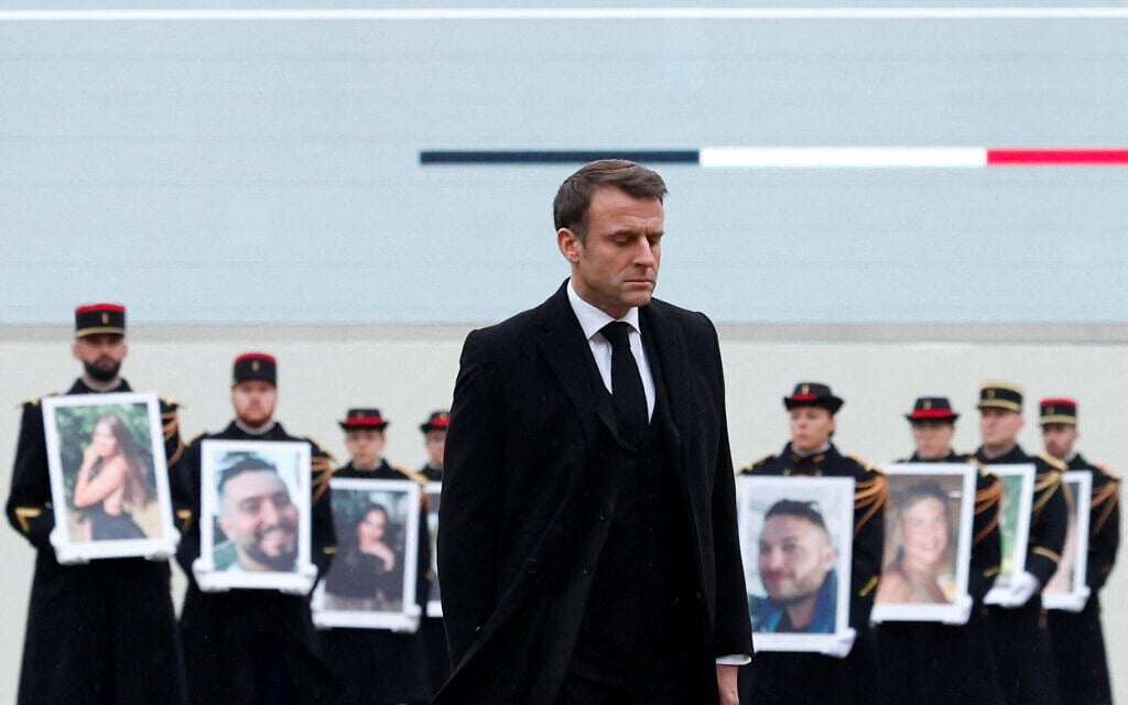 נשיא צרפת עמנואל מקרון עובר על פני משמרות הרפובליקה המחזיקים תמונות של אזרחי צרפת שנרצחו במתקפת חמאס בשבעה באוקטובר, 7 בפברואר 2024 (צילום: GONZALO FUENTES / POOL / AFP)