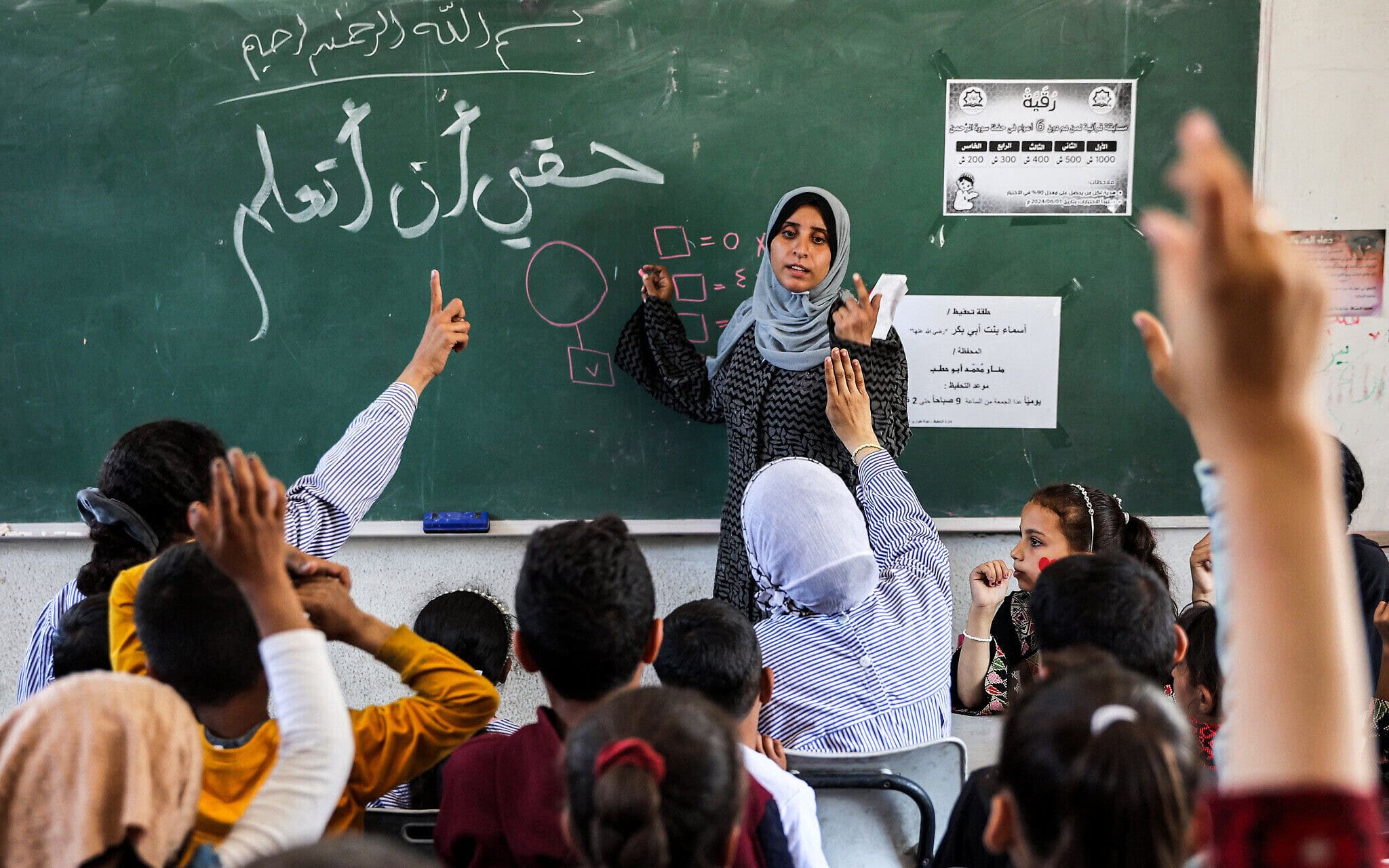 ארכיון: אישה מלמדת ילדים חשבון בכיתת בית ספר המנוהל על ידי אונר&quot;א במחנה הפליטים שאטי ממערב לעיר עזה, 7 במאי 2024 (צילום: AFP)