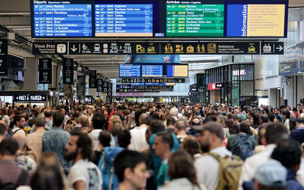 נוסעים מתאספים סביב לוחות היציאה וההגעה בתחנת הרכבת מונפרנאס בפריז ב-26 ביולי 2024 לאחר הפגיעה רשת הרכבות המהירות בצרפת (צילום: Thibaud MORITZ / AFP) נוסעים מתאספים סביב לוחות היציאה וההגעה בתחנת הרכבת מונפרנאס בפריז ב-26 ביולי 2024 לאחר הפגיעה רשת הרכבות המהירות בצרפת (צילום: Thibaud MORITZ / AFP)