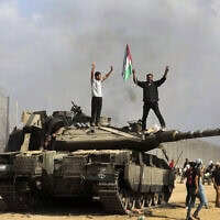 פלסטינים מניפים את הדגל הלאומי וחוגגים סביב טנק ישראלי הרוס ליד גדר הגבול בדרום רצועת עזה, ממזרח לחאן יונס, 7 באוקטובר 2023 (צילום: AP Photo/Yousef Masoud) פלסטינים מניפים את הדגל הלאומי וחוגגים סביב טנק ישראלי הרוס ליד גדר הגבול בדרום רצועת עזה, ממזרח לחאן יונס, 7 באוקטובר 2023 (צילום: AP Photo/Yousef Masoud)