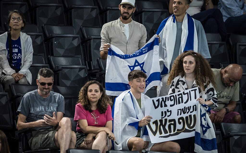 אוהדים ישראלים מחזיקים שלט לכבוד המתעמל ארטיום דולגופיאט במשחקים האולימפיים בפריז. 3 באוגוסט 2024 (צילום: הוועד האולימפי בישראל) אוהדים ישראלים מחזיקים שלט לכבוד המתעמל ארטיום דולגופיאט במשחקים האולימפיים בפריז. 3 באוגוסט 2024 (צילום: הוועד האולימפי בישראל)