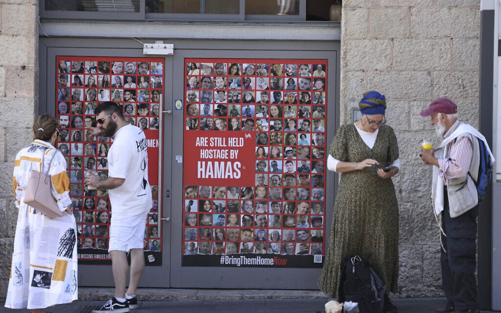אנשים עומדים לצד תמונות החטופים בירושלים, 13 באוקטובר 2024 (צילום: HAZEM BADER / AFP)
