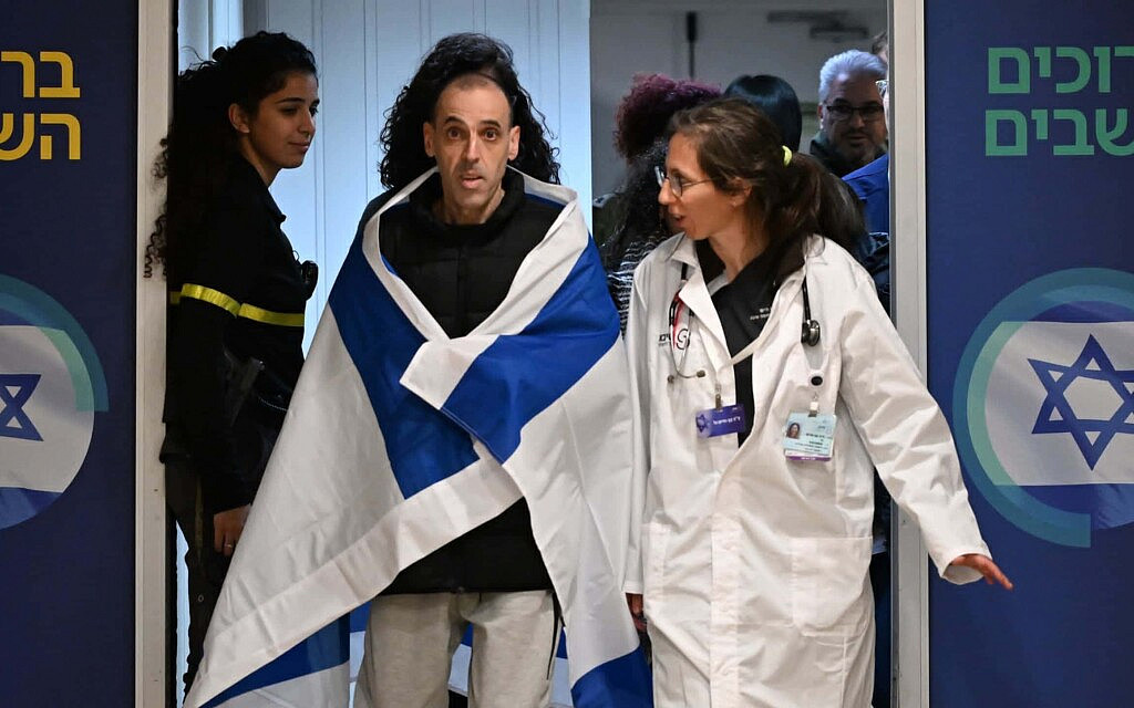 החטוף ששוחרר אלי שרעבי עטוף בדגל ישראל, עם הגעתו לבית החולים שיבא, 8 בפברואר 2025 (צילום: חיים צח / לע"מ) החטוף ששוחרר אלי שרעבי עטוף בדגל ישראל, עם הגעתו לבית החולים שיבא, 8 בפברואר 2025 (צילום: חיים צח / לע"מ)