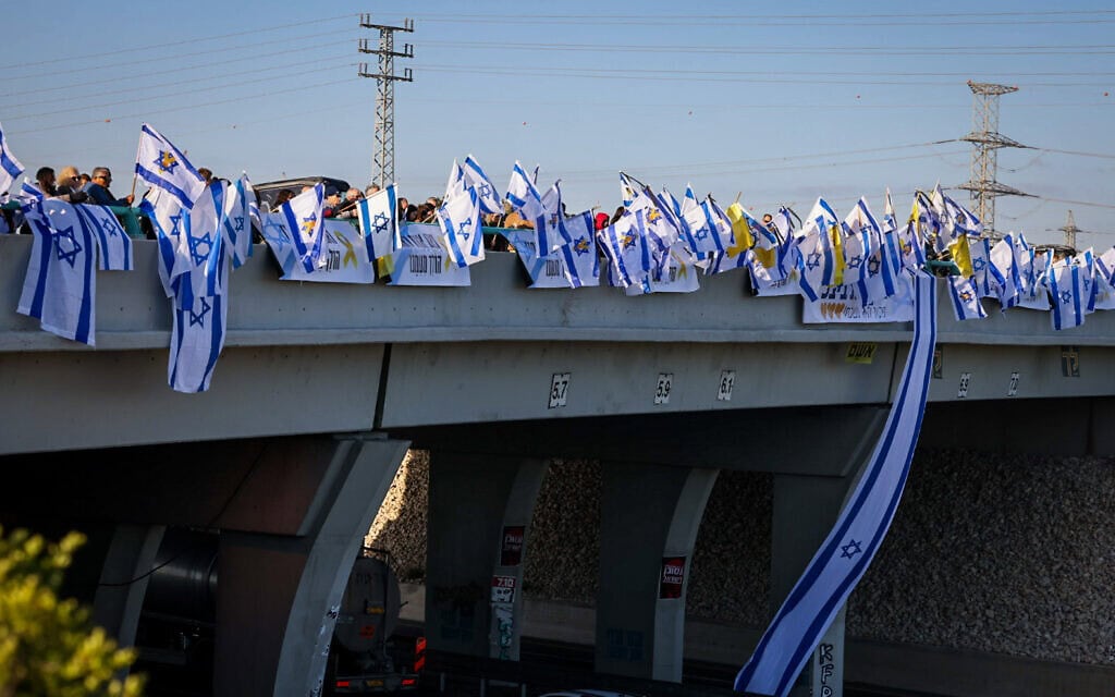 המונים עם דגלים במסע ההלוויה של שירי, אריאל וכפיר ביבס על הגשר בצומת גן יבנה. 26 בפברואר 2025 (צילום: יוסי אלוני/פלאש90) המונים עם דגלים במסע ההלוויה של שירי, אריאל וכפיר ביבס על הגשר בצומת גן יבנה. 26 בפברואר 2025 (צילום: יוסי אלוני/פלאש90)