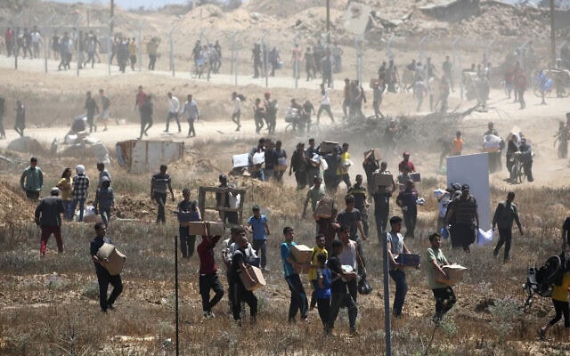 פלסטינים נושאים קופסאות סיוע הומניטרי מטעם קרן הסיוע לעזה (GHF) ממרכז חלוקה במרכז רצועת עזה, 29 במאי 2025 (צילום: Eyad BABA / AFP) פלסטינים נושאים קופסאות סיוע הומניטרי מטעם קרן הסיוע לעזה (GHF) ממרכז חלוקה במרכז רצועת עזה, 29 במאי 2025 (צילום: Eyad BABA / AFP)