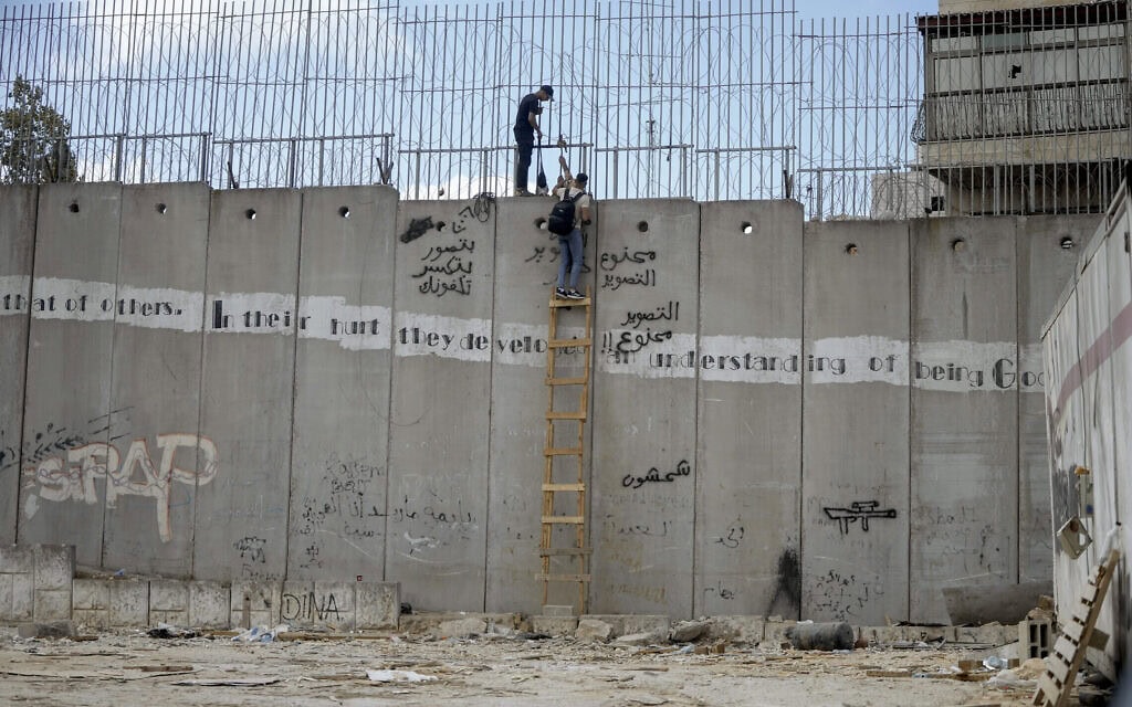 גברים פלסטינים מטפסים על גדר ההפרדה בעיירה א־ראם כדי לחצות באופן לא חוקי לירושלים, 15 בספטמבר 2024 (צילום: AP Photo/Mahmoud Illean) גברים פלסטינים מטפסים על גדר ההפרדה בעיירה א־ראם כדי לחצות באופן לא חוקי לירושלים, 15 בספטמבר 2024 (צילום: AP Photo/Mahmoud Illean)