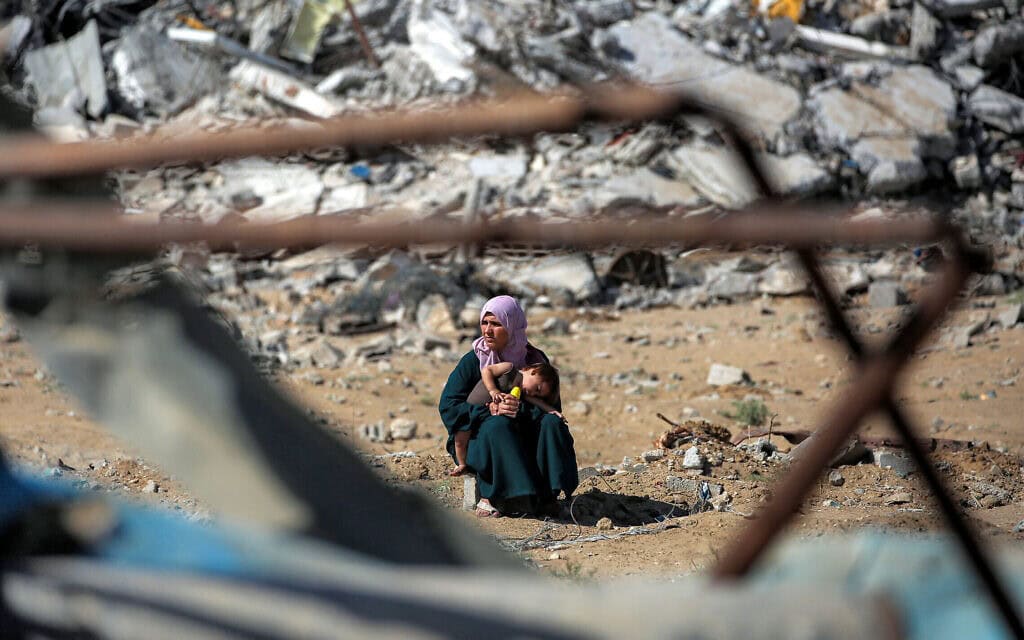 אישה פלסטינית יושבת עם בנה על הריסות מה שהיה בעבר ביתה בעיר עזה, 10 באוקטובר 2025 (צילום: Eyad BABA / AFP) אישה פלסטינית יושבת עם בנה על הריסות מה שהיה בעבר ביתה בעיר עזה, 10 באוקטובר 2025 (צילום: Eyad BABA / AFP)