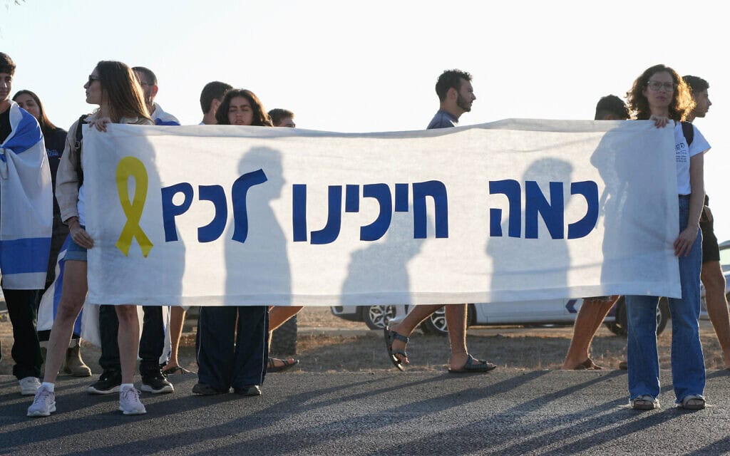 ישראלים מתקבצים עם שלטי תמיכה בחטופים השבים בדרום הארץ ביום השחרור, 13 באוקטובר 2025 (צילום: MAYA LEVIN / AFP)