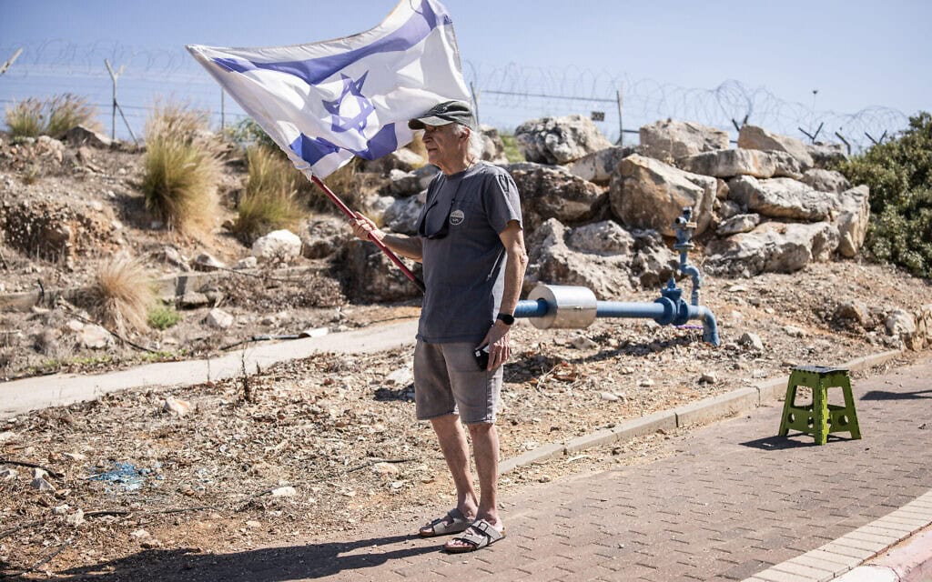 אדם הנושא דגל ממתין בצד הדרך לשיירה הנושאת את ארונו של חלל צה"ל תמיר נמרודי, המובא לקבורה בבית העלמין הצבאי בכפר סבא, 16 באוקטובר 2025 (צילום: JOHN WESSELS / AFP) אדם הנושא דגל ממתין בצד הדרך לשיירה הנושאת את ארונו של חלל צה"ל תמיר נמרודי, המובא לקבורה בבית העלמין הצבאי בכפר סבא, 16 באוקטובר 2025 (צילום: JOHN WESSELS / AFP)