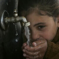 ילדה פלסטינית שותה מים מברז במטה אונר"א בחאן יונס, רצועת עזה, 27 בינואר 2010