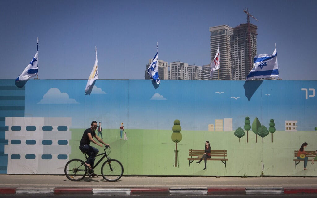 גבר רוכב על אופניים חשמליים סמוך לציור קיר שהוצב ליד אתר בנייה ברמת גן, סמוך לתל אביב. 29 באפריל 2015 (צילום: מרים אלסטר/פלאש90) גבר רוכב על אופניים חשמליים סמוך לציור קיר שהוצב ליד אתר בנייה ברמת גן, סמוך לתל אביב. 29 באפריל 2015 (צילום: מרים אלסטר/פלאש90)