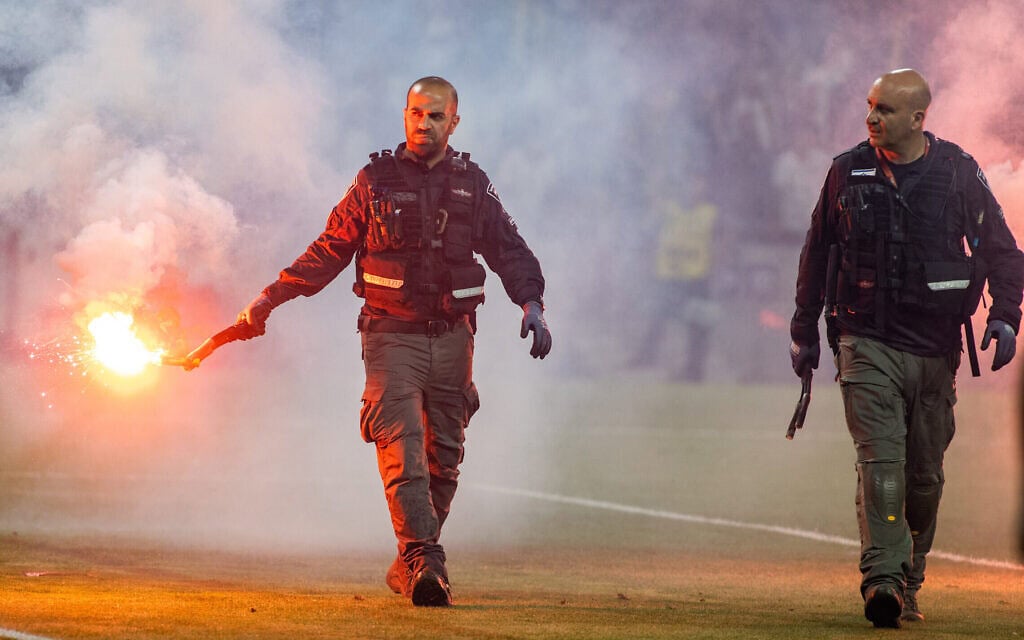 שוטרים מפנים אבוקה שהושלכה למגרש באצטדיון סמי עופר בגמר גביע המדינה בין מכבי נתניה וביתר ירושלים במאי 2023 (צילום: אורן בן חקון/פלאש90)