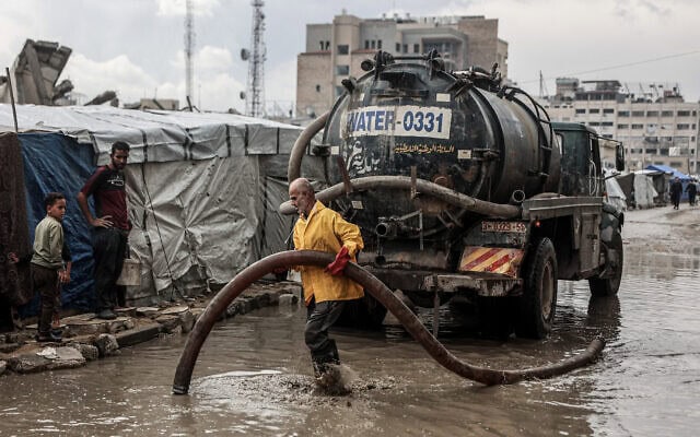 פלסטיני מפנה מים מהכביש סמוך למחנה אוהלים אחרי הגשם הראשון בעיר עזה ב־14 בנובמבר 2025 (צילום: Omar AL-QATTAA / AFP) פלסטיני מפנה מים מהכביש סמוך למחנה אוהלים אחרי הגשם הראשון בעיר עזה ב־14 בנובמבר 2025 (צילום: Omar AL-QATTAA / AFP)
