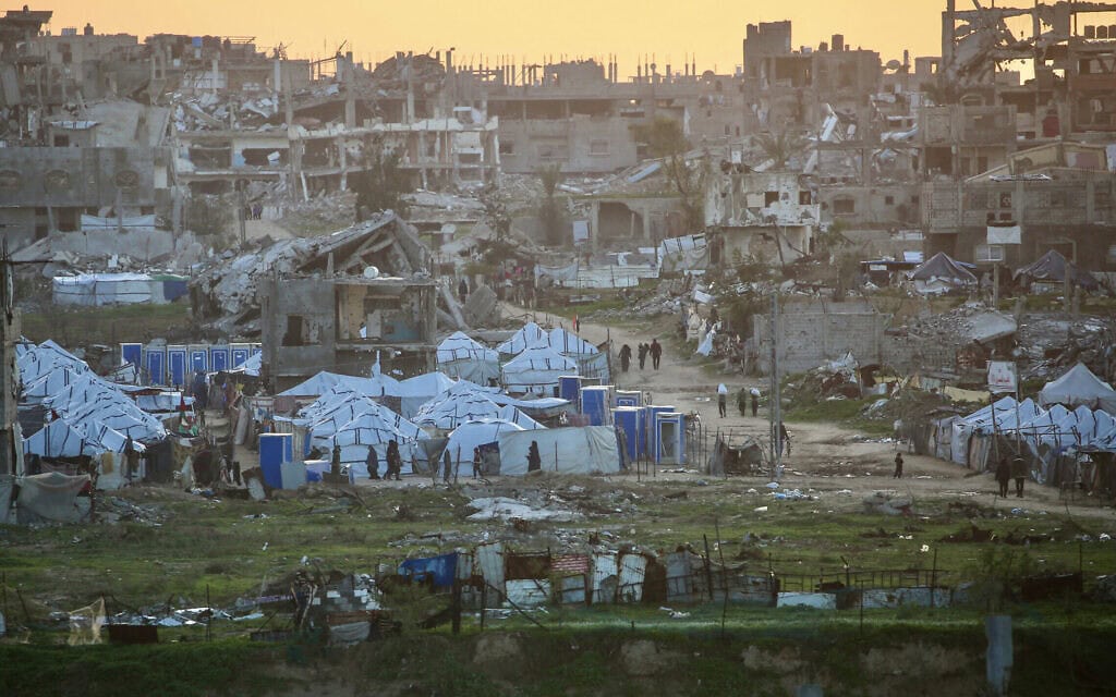 פלסטינים חולפים על פני מבנים הרוסים במחנה הפליטים נוסייראת שבמרכז רצועת עזה, 31 בדצמבר 2025 (צילום: Eyad Baba / AFP) פלסטינים חולפים על פני מבנים הרוסים במחנה הפליטים נוסייראת שבמרכז רצועת עזה, 31 בדצמבר 2025 (צילום: Eyad Baba / AFP)