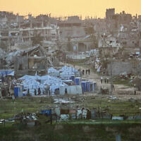 פלסטינים חולפים על פני מבנים הרוסים במחנה הפליטים נוסייראת שבמרכז רצועת עזה, 31 בדצמבר 2025 (צילום: Eyad Baba / AFP) פלסטינים חולפים על פני מבנים הרוסים במחנה הפליטים נוסייראת שבמרכז רצועת עזה, 31 בדצמבר 2025 (צילום: Eyad Baba / AFP)