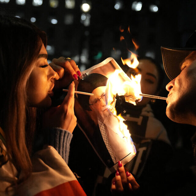 מפגינים מצטלמים בזמן שהם שורפים תמונה של האייתוללה עלי חמינאי בלונדון, 11 בינואר 2026 (צילום: CARLOS JASSO / AFP) מפגינים מצטלמים בזמן שהם שורפים תמונה של האייתוללה עלי חמינאי בלונדון, 11 בינואר 2026 (צילום: CARLOS JASSO / AFP)