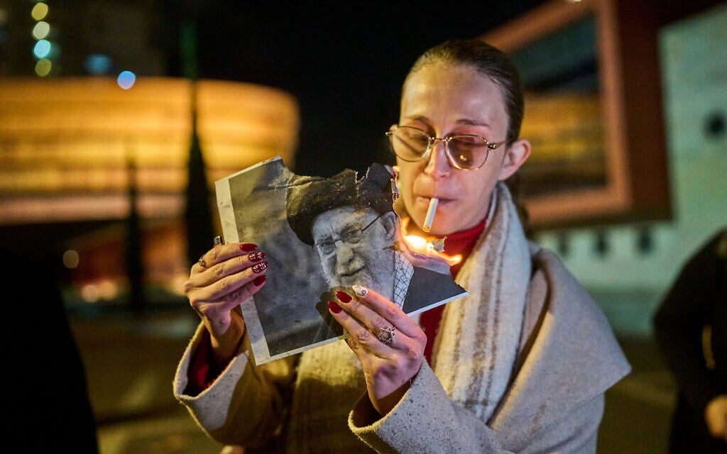 מפגינה מציתה סיגריה עם תמונה של האיתוללה עלי חמינאי בעצרת תמיכה במחאה האיראנית שנערכה בחולון, 14 בינואר 2026 (צילום: AP Photo/Ohad Zwigenberg) מפגינה מציתה סיגריה עם תמונה של האיתוללה עלי חמינאי בעצרת תמיכה במחאה האיראנית שנערכה בחולון, 14 בינואר 2026 (צילום: AP Photo/Ohad Zwigenberg)