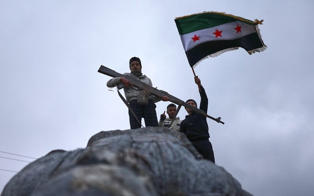 תושבים מניפים דגל סוריה מעל פסל שהופל בטבקה שבמזרח סוריה, לאחר שכוחות המשטר הסורי השתלטו על העיר מידי כוחות SDF הנתמכים בידי ארה"ב, 18 בינואר 2026 (צילום: Ghaith Alsayed / AP) תושבים מניפים דגל סוריה מעל פסל שהופל בטבקה שבמזרח סוריה, לאחר שכוחות המשטר הסורי השתלטו על העיר מידי כוחות SDF הנתמכים בידי ארה"ב, 18 בינואר 2026 (צילום: Ghaith Alsayed / AP)