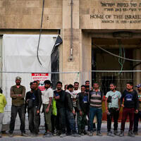 עובדי בנייה זרים עומדים מחוץ למוזיאון הכנסת בזמן בנייתו, 28 ביולי 2024