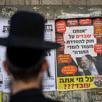 פוסטר המציג את יו"ר ש"ס אומר:
"אנחנו עובדים על חוק להסדרת מעמד לומדי תורה", ומתחתיו הכיתוב: "על מי אתה עובד?" בשכונת מאה שערים בירושלים. 28 באוקטובר 2025